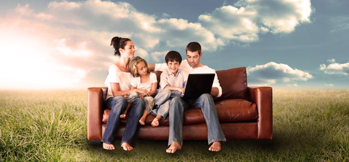 Young family sitting on couch sharing a laptop.