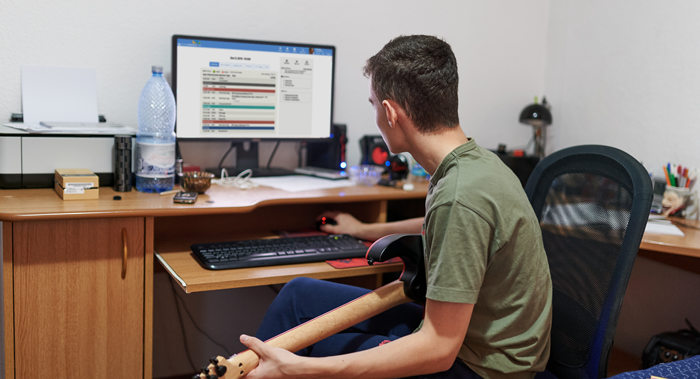 Man with guitar in front of computer